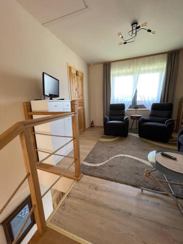 ein Wohnzimmer mit einer Treppe und ein Wohnzimmer mit Stühlen in der Unterkunft Przyszowa 441 in Przyszowa