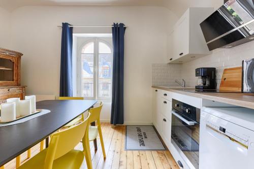 a kitchen with a black counter and yellow chairs at Appartements de l'Abbaye - A 10 minutes de Disneyland in Lagny