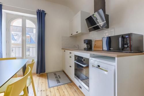 a kitchen with white appliances and a table with chairs at Appartements de l'Abbaye - A 10 minutes de Disneyland in Lagny