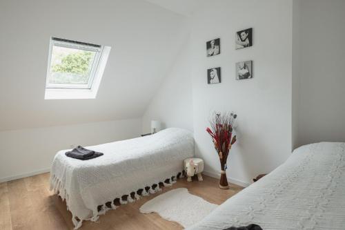 Cette chambre blanche dispose de deux lits et d'une fenêtre. dans l'établissement Villa Brelevenez 7 chambres Spa Piscine Jardin, à Lannion