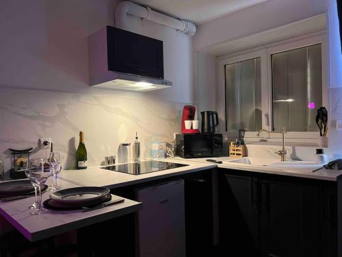 a kitchen with a sink and a counter with wine glasses at Red love-room / Balnéo & plus ! in Souppes-sur-Loing