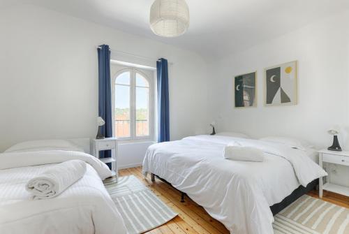 a white bedroom with two beds and a window at Le Magnolia - A 10 minutes de Disneyland in Lagny