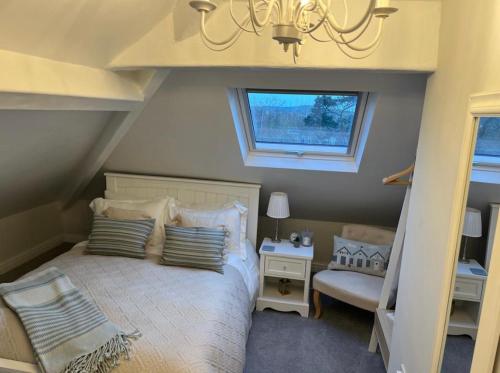 um quarto com uma cama com um lustre e uma janela em Castellor Bed & Breakfast em Cemaes Bay