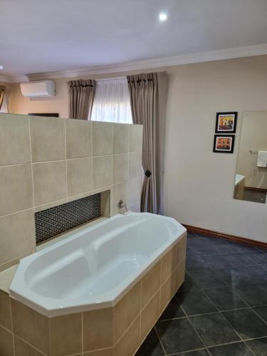 Cette chambre comprend une salle de bains pourvue d'une grande baignoire. dans l'établissement Glen Marion Guest House, à Pretoria