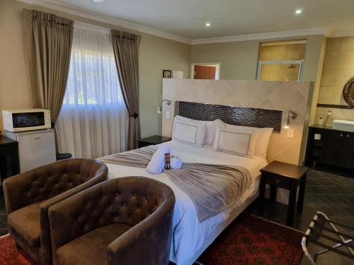 a hotel room with a large bed with two chairs at Glen Marion Guest House in Pretoria