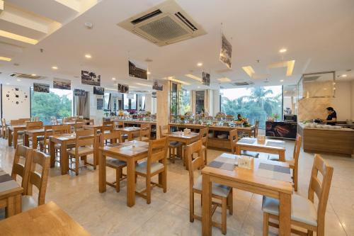 a restaurant with wooden tables and wooden chairs at An Vista Hotel in Nha Trang