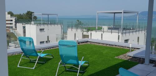 two blue chairs sitting on the grass on a balcony at Villapark Apartman B2 Fonyód in Fonyód