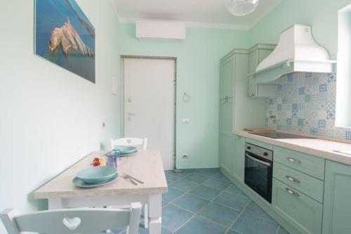 cocina con armarios blancos, mesa y sillas en Appartamento Sogno Marino, en Portoferraio