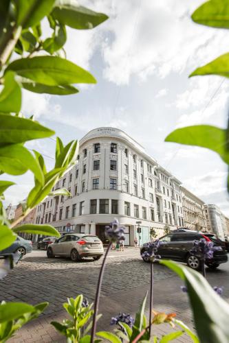 a large white building with cars parked in front of it at Luxury studio with a park view in Rīga