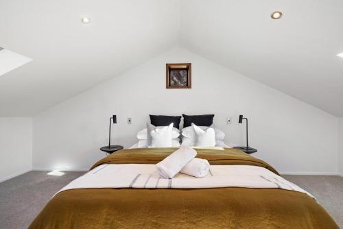 um quarto branco com uma cama grande e almofadas brancas em Beautifully styled central home em Queenstown