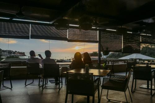 a group of people sitting at a table watching the sunset at Hotel Cala Saona & Spa in Cala Saona
