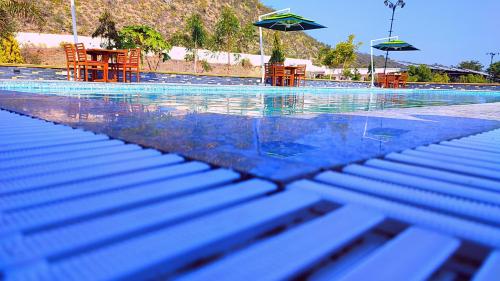 a swimming pool with tables and chairs and umbrellas at The Sky Imperial Nakoda Green Valley Resort in Nāthdwāra