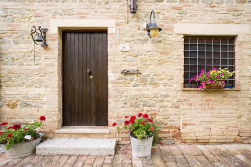 Montemaggiore al MetauroにあるCasale Dal Moroのドアと2つの花のバケツが付いたレンガ造りの建物