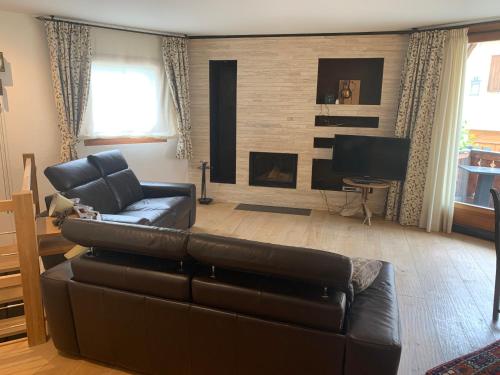 a living room with a leather couch and a television at chesa collina in Pontresina