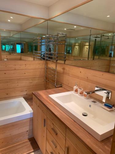 uma casa de banho com um lavatório, uma banheira e espelhos em chesa collina em Pontresina