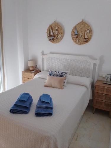 a bedroom with a white bed with blue towels on it at ADNANIa 2023 in La Herradura
