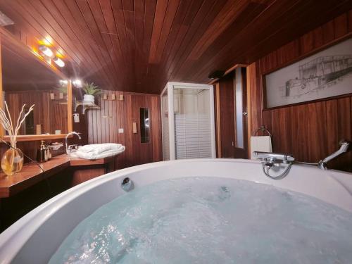 La salle de bains est pourvue d'une grande baignoire et de murs en bois. dans l'établissement Peniche relaxant, à Sèvres