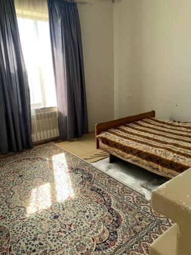a bedroom with a bed and a rug on the floor at Гостевой Домик Жайлау in Taraz