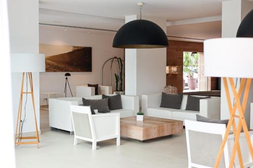 a living room with white furniture and a black ceiling at Hotel Cala Saona & Spa in Cala Saona