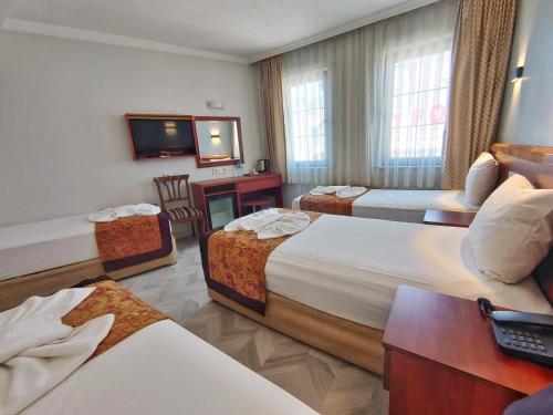 a hotel room with three beds and a television at Orient Mintur Hotel in Istanbul