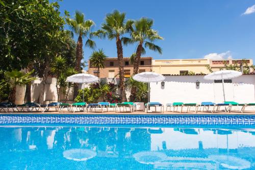 einen Pool mit Stühlen und Sonnenschirmen in der Unterkunft Hotel Avenida in Benicàssim