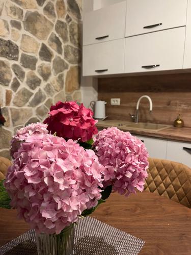 een vaas gevuld met roze bloemen op een tafel bij Madona di Sinj in Sinj