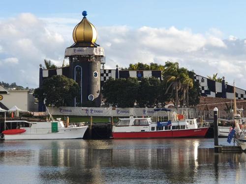 due barche sono ormeggiate in un porto turistico con un faro di On the water boat House a Whangarei