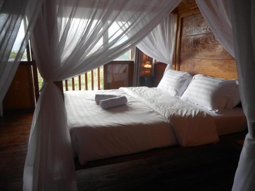 Schlafzimmer mit einem Bett mit weißer Bettwäsche und Kissen in der Unterkunft Villa Dukuh in Selat
