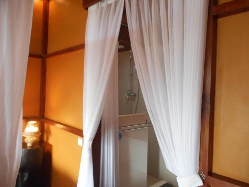 a bathroom with white curtains and a shower at Villa Dukuh in Selat