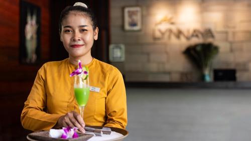 Una donna seduta a un tavolo con un drink di Lynnaya Urban River Resort a Siem Reap