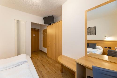 a bedroom with a desk and a mirror and a bed at Hotel Derby in Folgarida