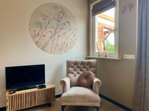 a living room with a chair and a television at Camping Lagewald Vakantiehuis in Groesbeek