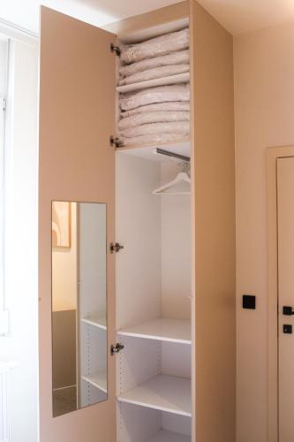 a closet with white shelves and a mirror at Maison d’Arnaud in Ghent