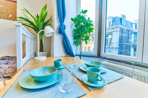 a table with bowls and plates on a table with a window at Studio Hyper centre - Cathédrale in Liège