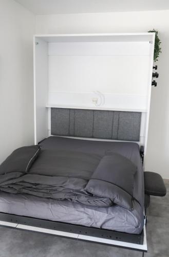 Ce lit se trouve dans un dortoir doté d'un mur blanc. dans l'établissement Studio rénové centre ville, clim et terrasse, à Montpellier