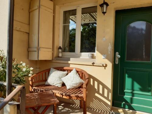 a bench on the porch of a house with a green door at Omas Obstkiste in Stockach