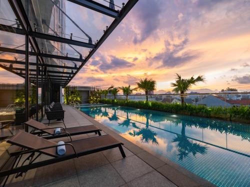 a swimming pool on the roof of a building with a sunset at Crowne Plaza Danang City Centre by IHG in Da Nang