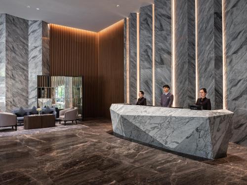 ダナンにあるCrowne Plaza Danang City Centre by IHGの大理石のカウンターに3人が座っているロビー
