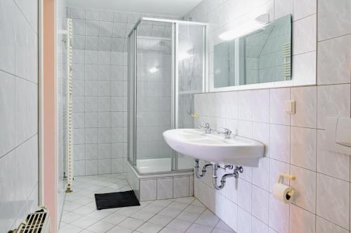 ein weißes Bad mit einem Waschbecken und einer Dusche in der Unterkunft Ferienhausanlage Sonne in Dranske