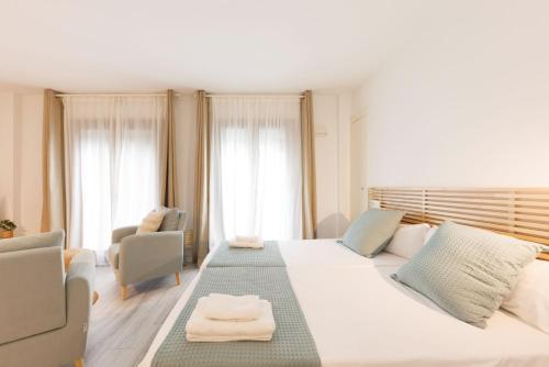 a bedroom with a large white bed and two chairs at Bravissimo Plaça Catalunya 1-2, Studio apartment in Girona