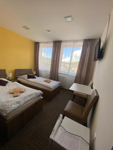 una habitación de hotel con 2 camas y una silla en Penzion Teplanka, en Považská Bystrica