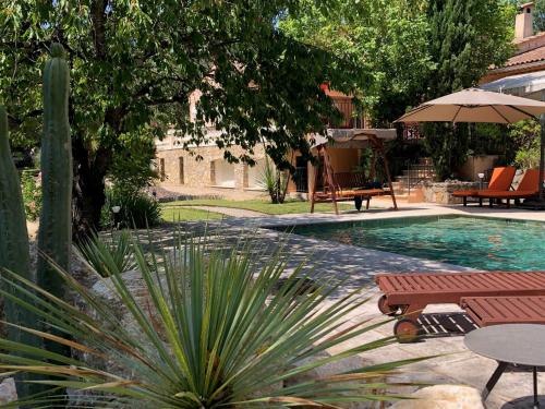 a swimming pool with two benches and an umbrella at Ekin ô reV Gîte Fontessante in Montauroux
