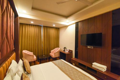 a hotel room with a bed and a flat screen tv at Hotel Swagat Suites in Haridwār