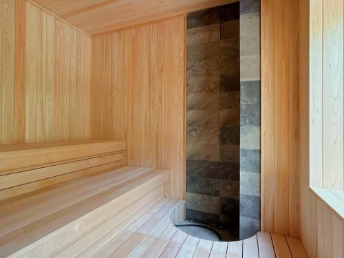 a sauna with a wooden floor and a stone wall at Suigan in Jozankei
