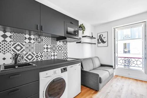 une cuisine avec un lave-linge et un canapé dans l'établissement Cosy Studio - Pyrénées, à Paris