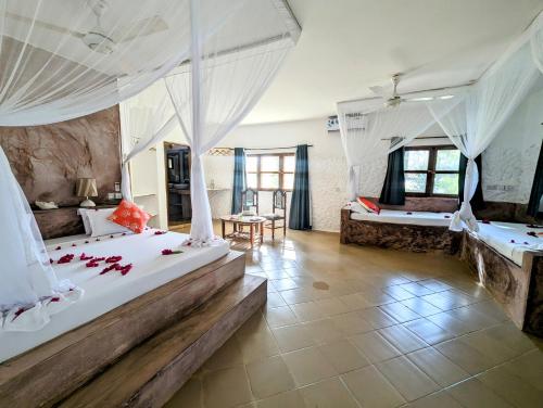 a bedroom with two beds with white drapes at Bahati Villa in Kiwengwa