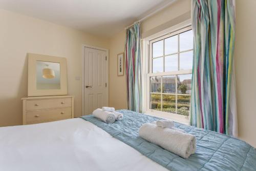 a bedroom with a bed and a window with towels at Sands End in Camber