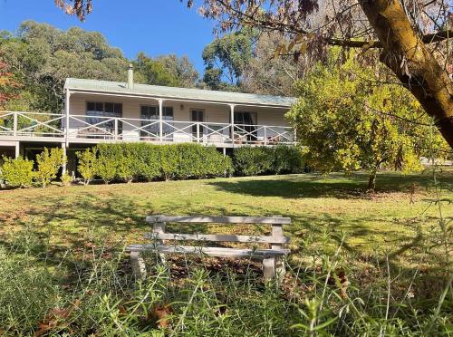 a bench sitting in the grass in front of a house at Rivendell Cottage in Steels Creek