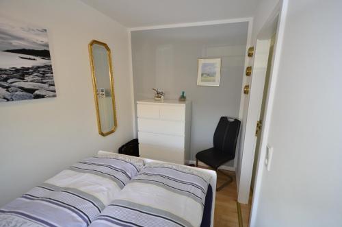 a bedroom with a bed and a mirror and a chair at Ferienwohnung Skovsende 25 in Glücksburg