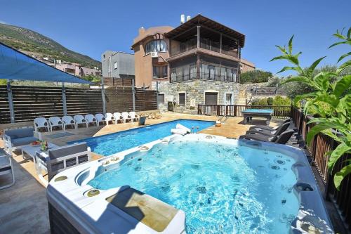 a swimming pool with chairs and a house in the background at הרמוניה בכפר - וילה מקסימה עם בריכה פרטית מחוממת וג'קוזי in ‘Ein el Asad